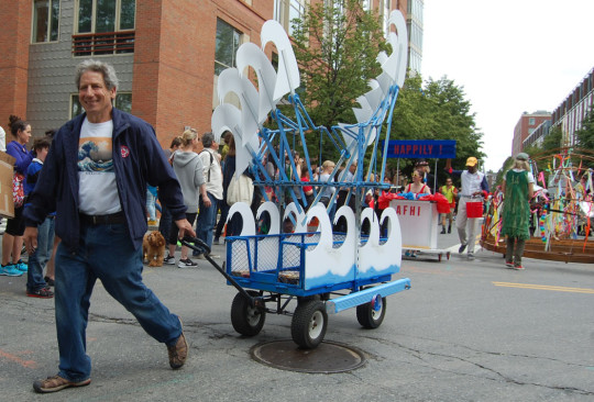 “Tsunami Wave Machine (Homage to Hokusai)” by Steve Hahn of Stoughton has a crankshaft that makes foam-board waves spin. Also a tube rocks to make ocean sounds as he pulls the wagon. “The important part is the effect, to make people happy, especially children. Little kids love to see machinery because they don’t get to see anything anymore.” (Greg Cook)